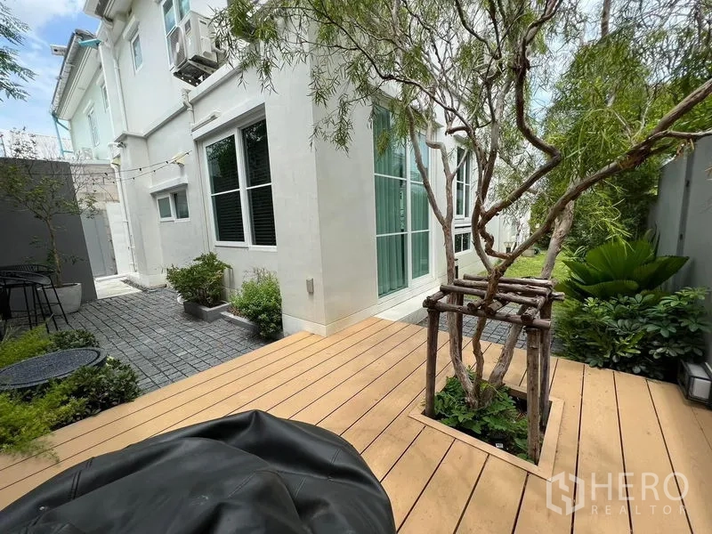 บ้าน ให้เช่าหรือขายในPrawet, Bangkok - ลานหลังบ้านทำเด็คไม้ มีต้นไม้ใหญ่ และทางเดินพื้นบล็อก.