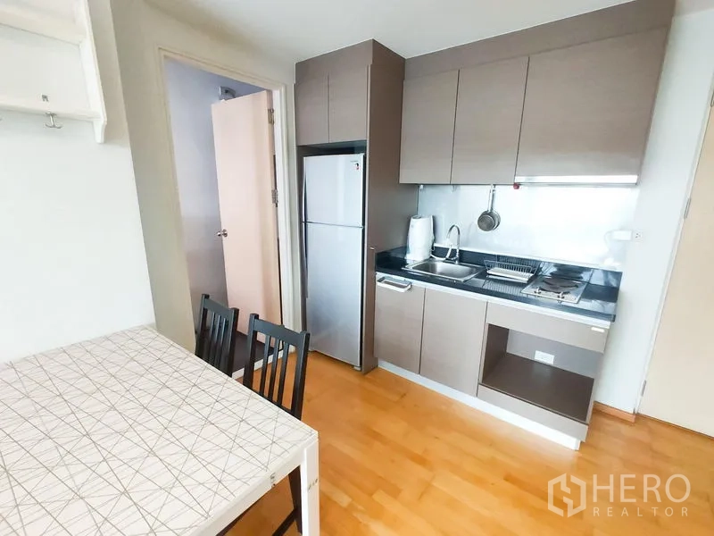 Condominium for rent in Khlong Toei, Bangkok - Spacious living area facing TV unit and shelving, connected to kitchen and dining zone.