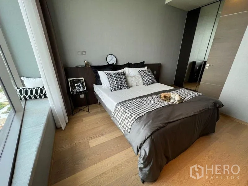 公寓 出租在Bang Rak, Bangkok - 温馨次卧，带窗边座位、格纹抱枕与木地板。