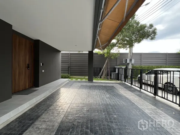 独立式住宅 出租在Prawet, Bangkok - 有顶车库、木质入户门与拼砖车道。