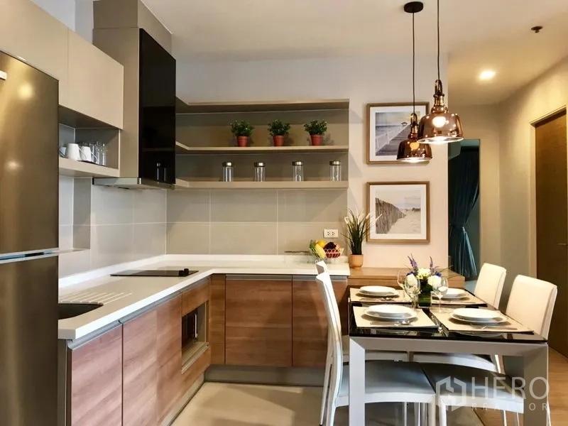 Condominium for rent in Khlong Toei, Bangkok - Modern L-shaped kitchen with open shelves, built-in hob and four-seat dining area.