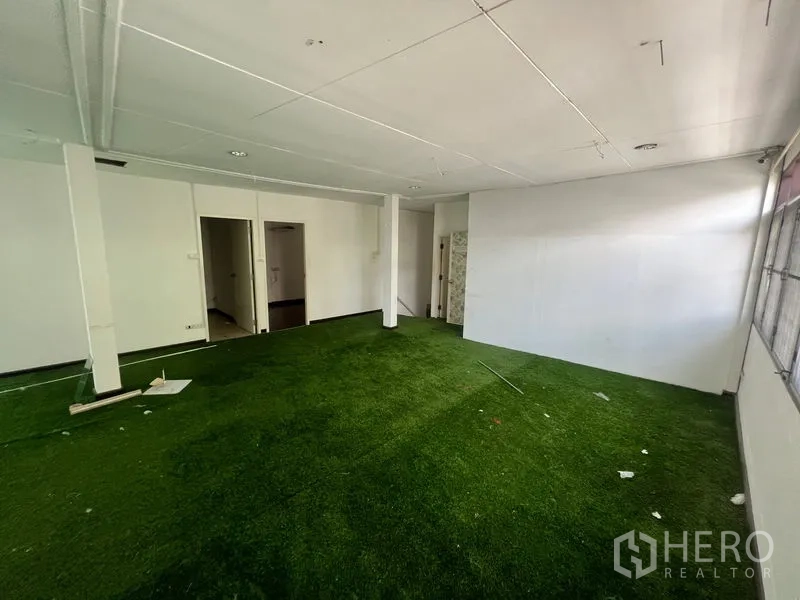 Retail Space for rent in Watthana, Bangkok - Open multipurpose space with artificial grass flooring and support pillars.