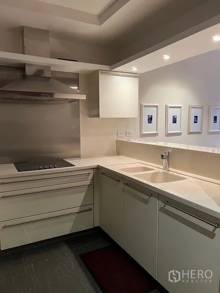 Condominium for rent in Pathum Wan, Bangkok - U-shaped kitchen with white cabinetry, cooktop, sink and recessed lighting.