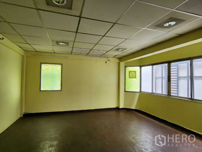 Retail Space for rent in Bang Rak, Bangkok - Empty retail room with yellow walls, drop ceiling with recessed lights, and wide windows bringing in natural light.