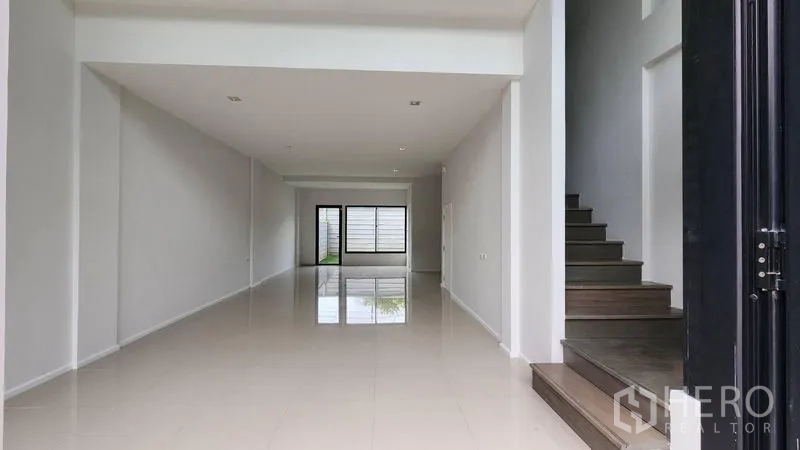 Home Office for rent - Ground-floor showroom area with double-height ceiling and staircase.