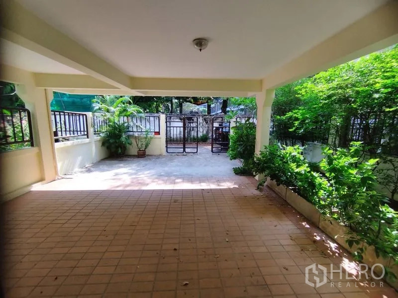 Detached House for rent in Watthana, Bangkok - Covered parking area looking toward the gated driveway and planters.