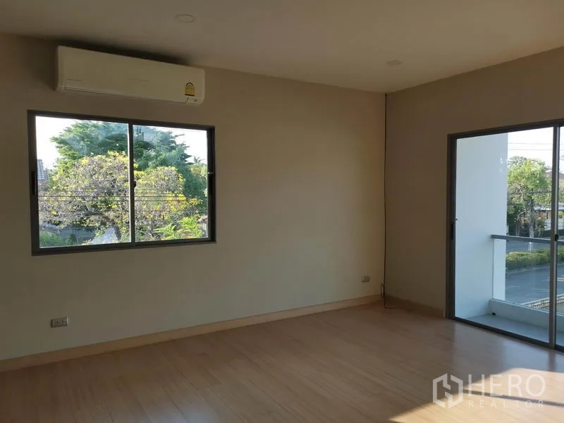 独立式住宅 出售在Nonthaburi - 卧室配空调，窗外绿树景观，并可通往阳台