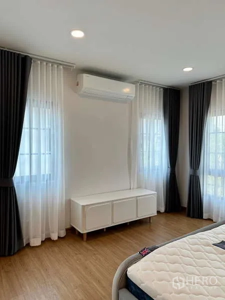 Detached House for rent in Bang Phli, Samut Prakan - Corner of bedroom with air conditioner, sheer curtains and low console cabinet.