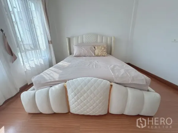 联排别墅 出租在Prawet, Bangkok - 采光充足的卧室，白色软包床与温暖木地板。