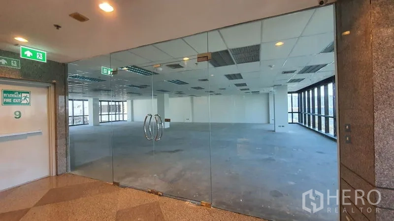 Office Space for rent in Watthana, Bangkok - Glass double-door entrance to a large open-plan office floor with grid ceiling and lights.