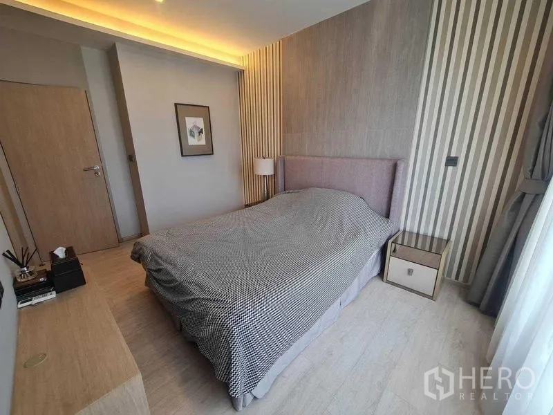 Condominium for sale - Bedroom view showing soft lighting, patterned walls and a city outlook through curtains.