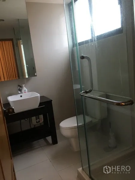 คอนโด ให้เช่าในPathum Wan, Bangkok - ห้องน้ำสมัยใหม่พร้อมตู้กระจกอาบน้ำ เคาน์เตอร์อ่างล้างหน้าสีขาว โถสุขภัณฑ์ และหน้าต่างฝ้า