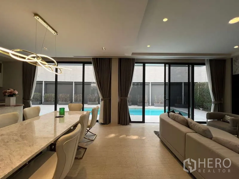 Detached House for rent in Suan Luang, Bangkok - Bright dining room with marble table, designer lighting and pool access.