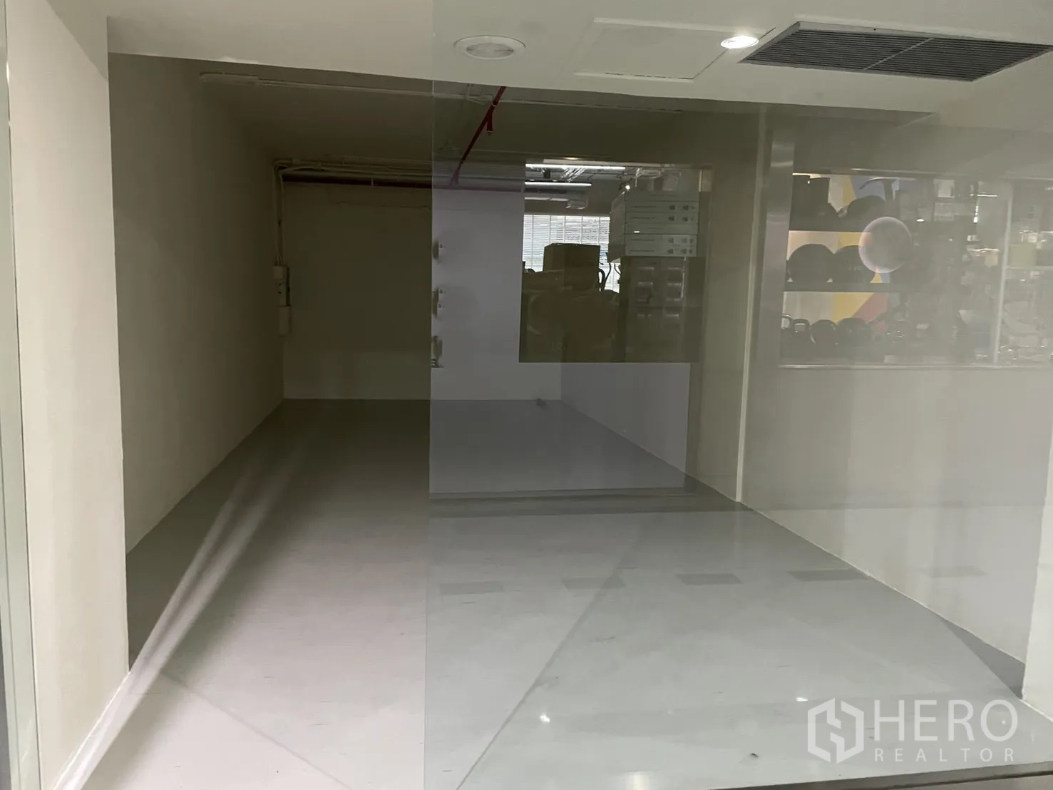 พื้นที่ขายของ for rent in Watthana, Bangkok - มุมมองผ่านผนังกระจกเต็มบานเข้าสู่ร้านว่าง พร้อมช่องลมแอร์และไฟฝ้า