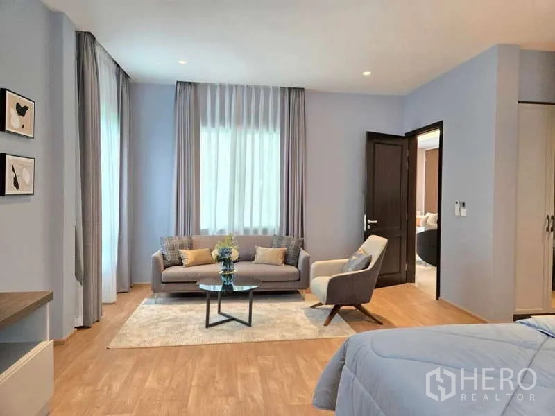 Detached House for rent or sale in Lat Krabang, Bangkok - Bedroom sitting area with sofa, armchair, and round coffee table.
