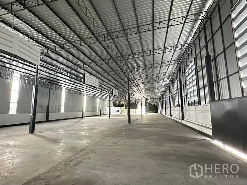 Warehouse for rent in Khan Na Yao, Bangkok - Bright warehouse aisle with ventilated louver windows, concrete floor and long‑span roof.