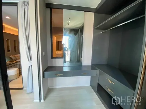 Condominium for rent in Pathum Wan, Bangkok - Walk-in closet with vanity desk, mirror and built-in storage beside the living area.