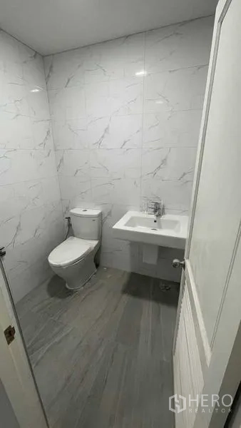 Townhouse for sale in Prawet, Bangkok - Clean bathroom with marble-effect wall tiles, toilet and sink.