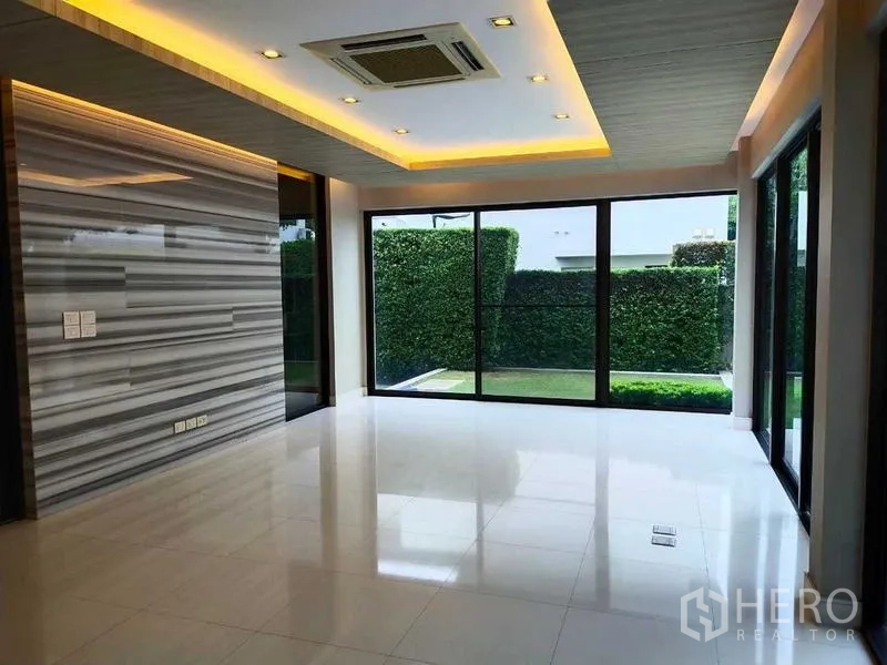 独立式住宅 出租或出售在Mueang Nonthaburi, Nonthaburi - 客厅敞阔，带大理石纹特色墙、筒灯与通向花园的推拉玻璃门。