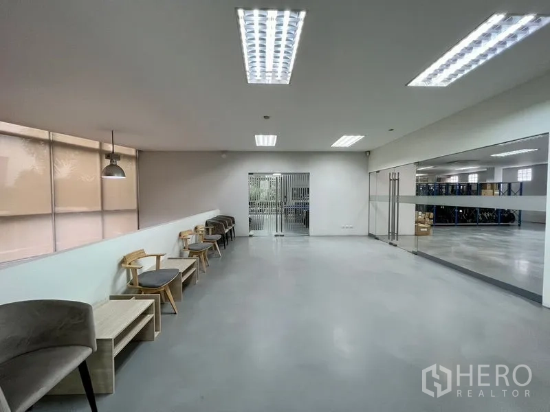 Office Space for rent in Bueng Kum, Bangkok - Wide multipurpose space with chairs along the wall, pendant lighting, and a glass partition to a storage area.