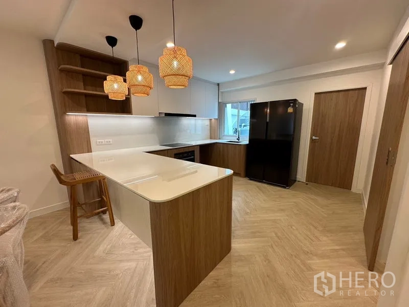 带办公室的家 出租在Khlong Toei, Bangkok - 现代L型厨房，白色台面、中岛吧台与黑色冰箱。
