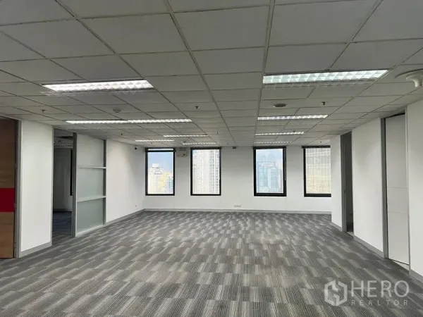 Office Space for rent in Khlong Toei, Bangkok - Large open office area with fluorescent lighting, windows and a glass partition wall.