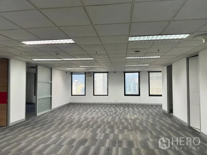 Office Space for rent in Khlong Toei, Bangkok - Large open office area with fluorescent lighting, windows and a glass partition wall.