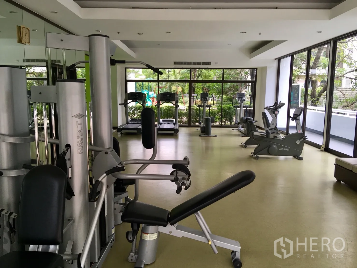 Condominium for rent or sale in Watthana, Bangkok - Fully equipped fitness room with weight machines and cardio facing large windows.