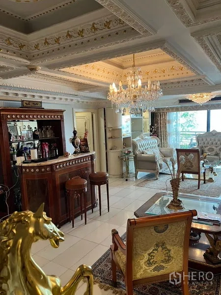 Condominium for sale in Khlong Toei, Bangkok - Mahogany Tower living room with ornate coffered ceiling, crystal chandelier, classic sofas and a built‑in bar.