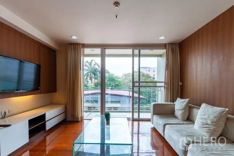 公寓 出租在Watthana, Bangkok - 客厅配L形沙发、玻璃茶几与绿色景观