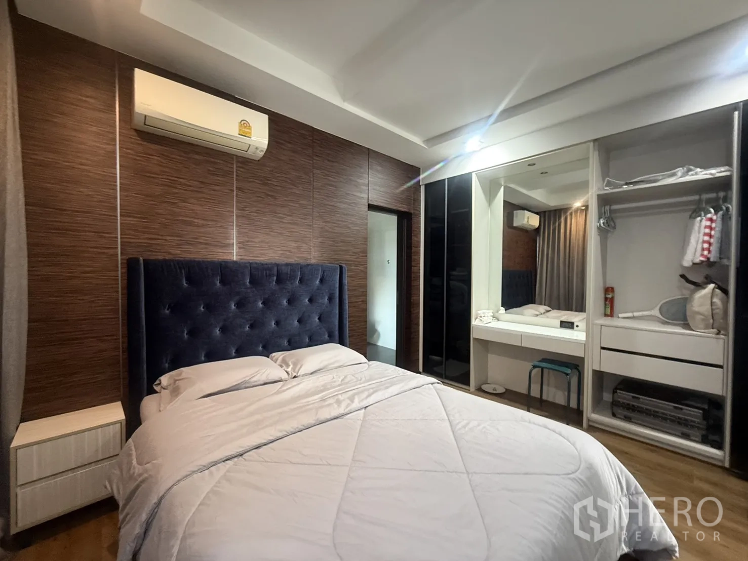 Detached House for rent in Bang Kapi, Bangkok - Guest bedroom with tufted navy headboard, built-in wardrobe, and dressing table.