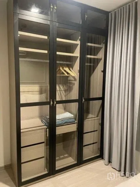 公寓 出租在Ratchathewi, Bangkok - 卧室内的内置玻璃门衣柜，带层板与抽屉。