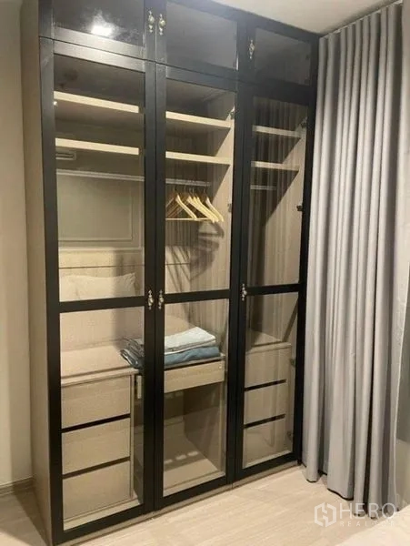 公寓 出租在Ratchathewi, Bangkok - 卧室内的内置玻璃门衣柜，带层板与抽屉。