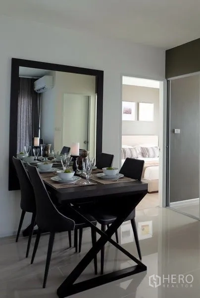 Condominium for sale in Khlong Toei, Bangkok - Contemporary dining area with large wall mirror and doorway leading to the bedroom.