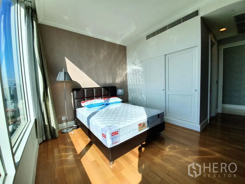 公寓 出租在Watthana, Bangkok - 卧室带大窗与充足采光，内置衣柜和木地板。