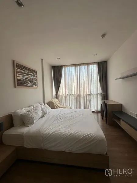 Condominium for rent in Watthana, Bangkok - Spacious bedroom with king bed, sheer curtains, desk, and floating shelves.