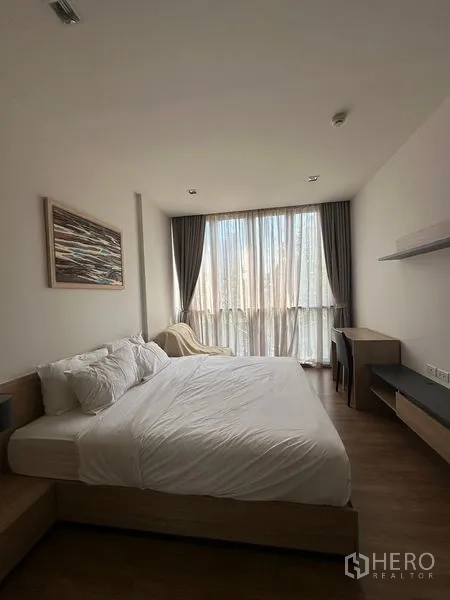Condominium for rent in Watthana, Bangkok - Spacious bedroom with king bed, sheer curtains, desk, and floating shelves.