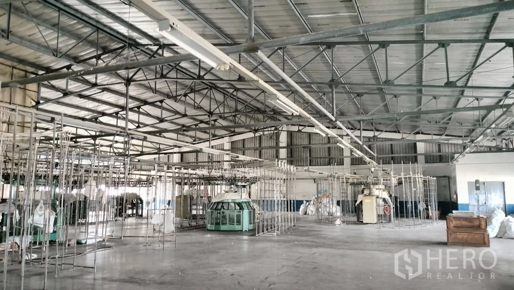 โรงงาน for rent in Lat Krabang, Bangkok - โครงหลังคาเหล็กพร้อมไฟแขวนเหนือพื้นที่ผลิตและโครงเครื่องจักร.