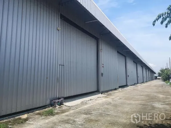 货栈 出租在Lam Luk Ka, Pathum Thani - 金属板外墙的仓库外立面，多个大型滑动门与车道出入口。