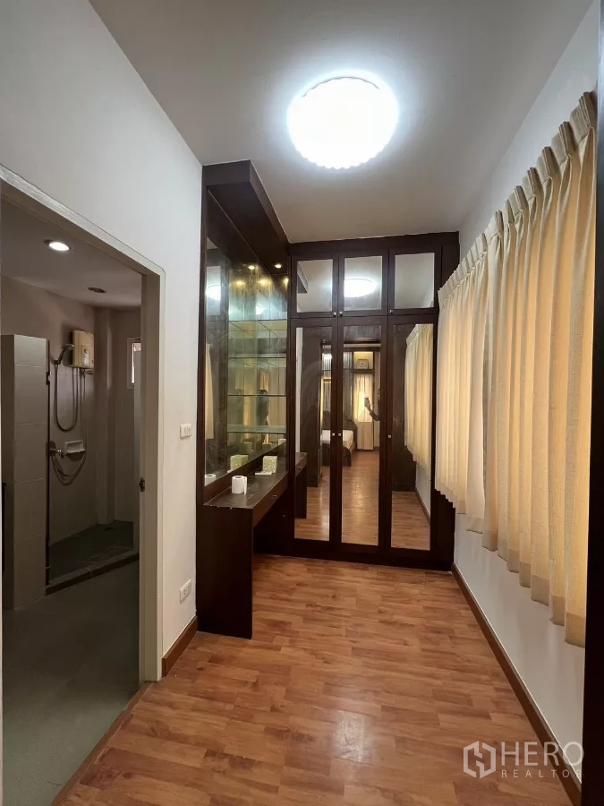 独立式住宅 出租在Bang Kapi, Bangkok - 步入式衣帽间走廊，玻璃展示柜与梳妆台，旁为卫生间。