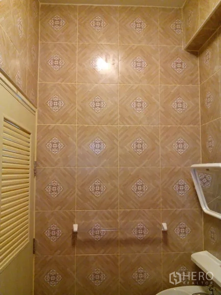Shophouse for rent in Phra Khanong, Bangkok - Tiled bathroom wall with louvered door and towel bar.