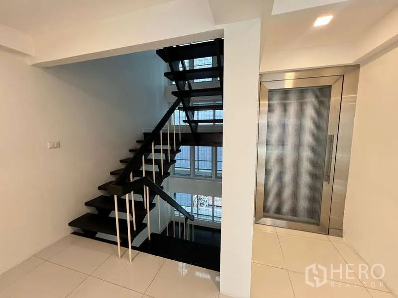 带办公室的家 出租在Khlong Toei, Bangkok - 室内黑色楼梯与不锈钢私家电梯，面向采光中庭。