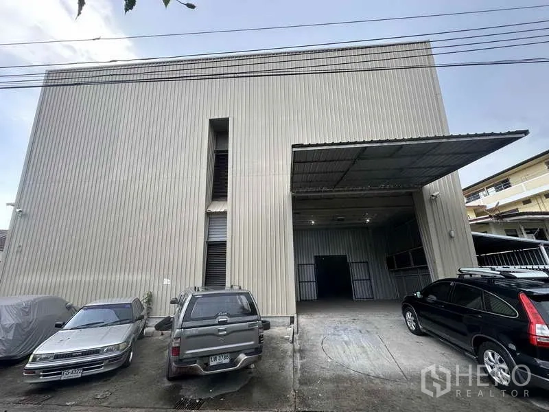 Home Office for rent in Bang Khen, Nonthaburi - Front facade of metal-clad warehouse with a covered loading bay and parking spaces.