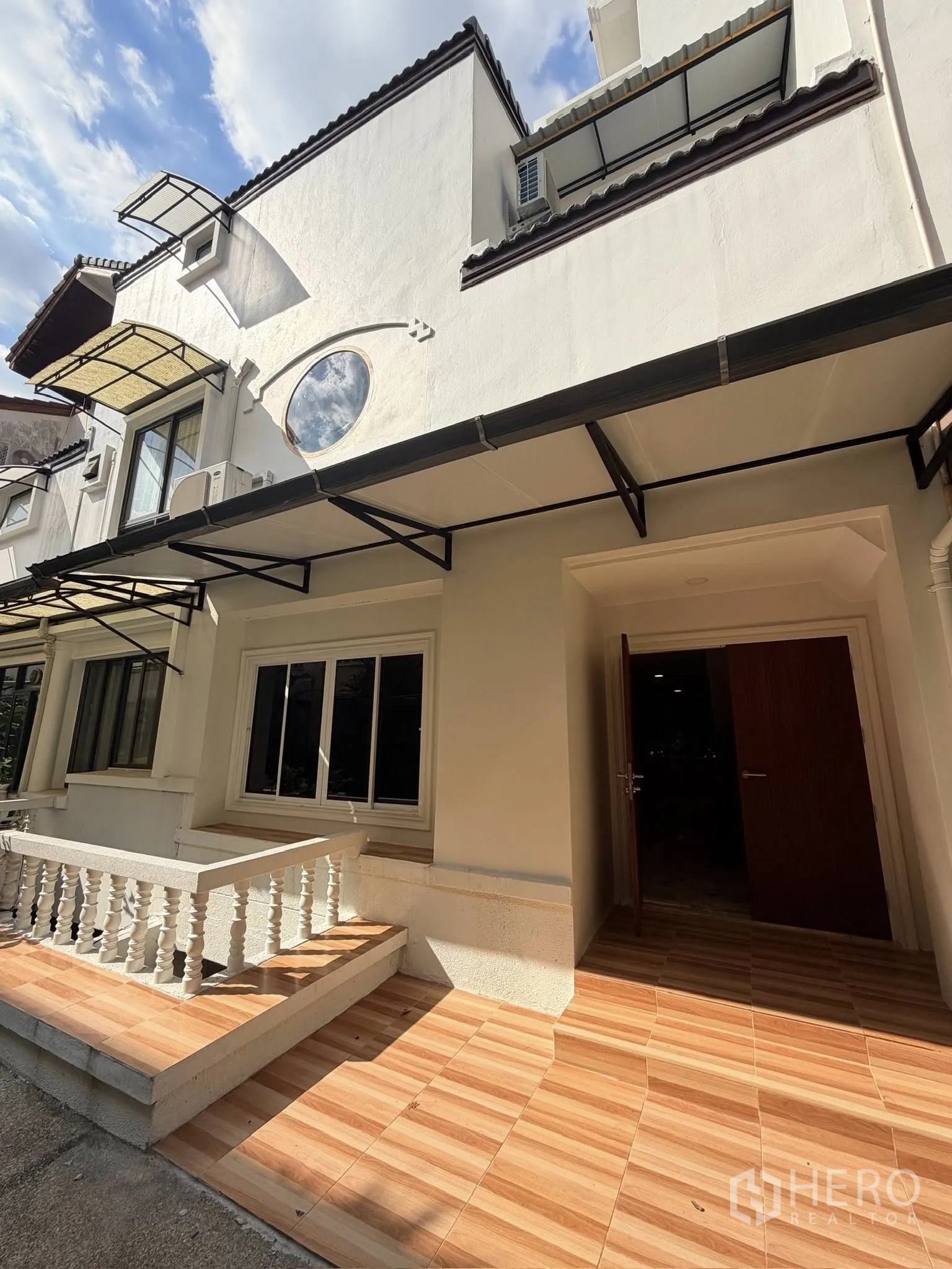 Townhouse for rent or sale in Yan Nawa, Bangkok - Three-storey white townhouse facade with tiled front patio and awnings.