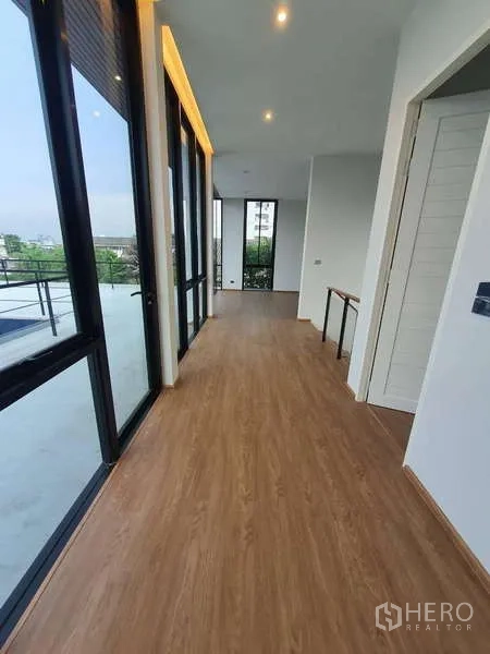 Detached House for rent in Phra Khanong, Bangkok - Upper hallway opening to a large terrace through full-height glass doors.