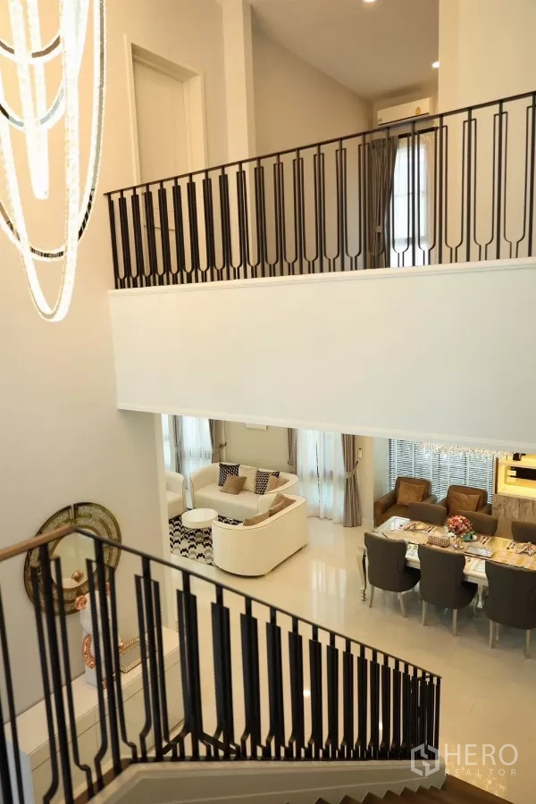 Detached House for rent or sale in Saphan Sung, Bangkok - View from staircase overlooking high-ceiling living and dining zones.