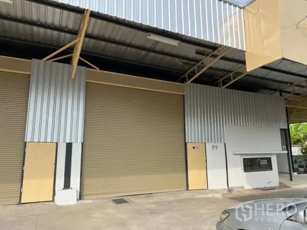 Warehouse for rent in Suan Luang, Bangkok - Exterior of Suan Luang warehouse with wide metal roll-up doors and a covered loading bay.