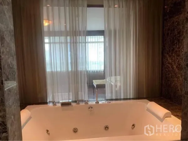 公寓 出租在Watthana, Bangkok - 大理石卫浴配大型按摩浴缸与头枕，玻璃隔断搭配纱帘。