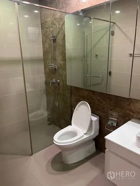 Detached House for rent in Wang Thonglang, Bangkok - Modern bathroom featuring a glass-enclosed shower, toilet, and mirrored storage cabinet.