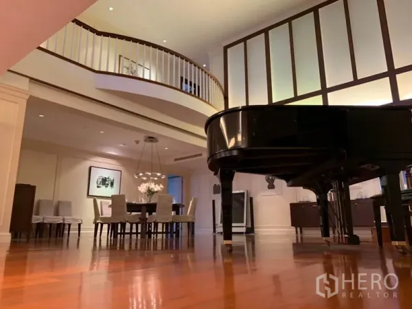 Condominium for rent or sale in Watthana, Bangkok - Open-plan lounge with a grand piano beneath a soaring ceiling and gallery railing.